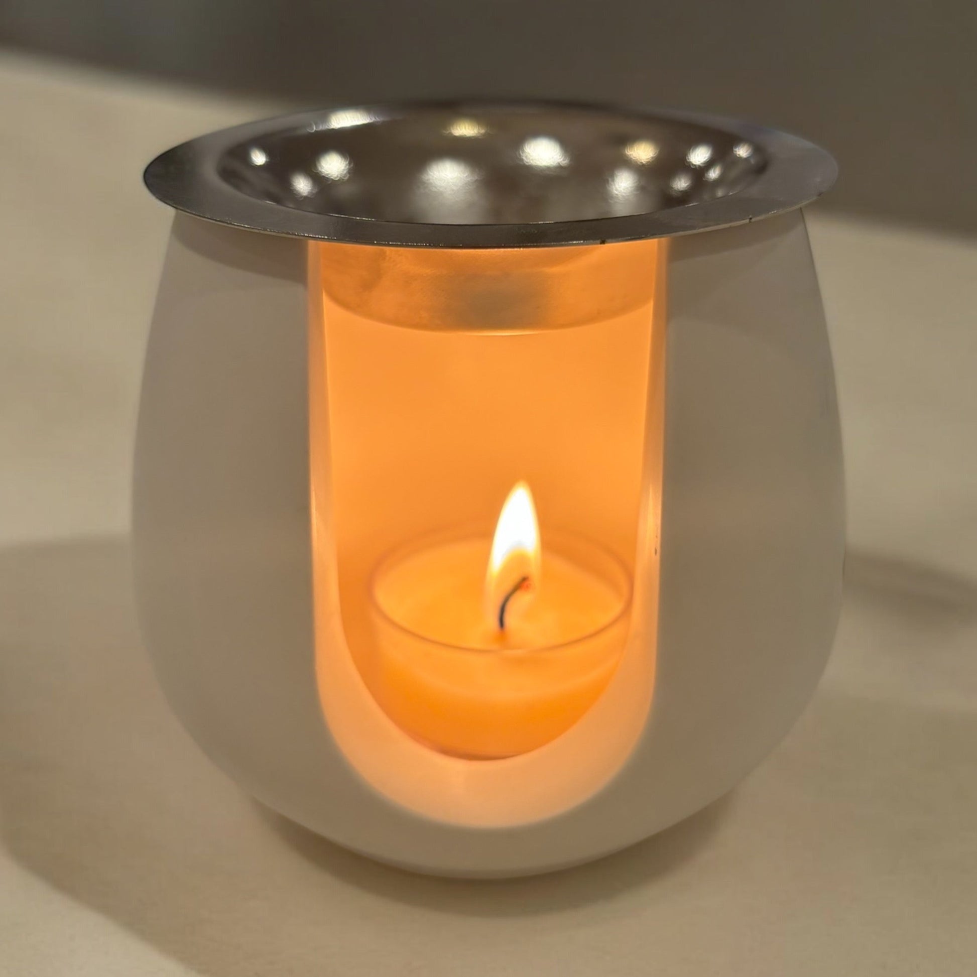 White paw-print wax melt burner made from eco-friendly jesmonite, featuring a lit tealight and melting wax, creating a cozy and aromatic atmosphere